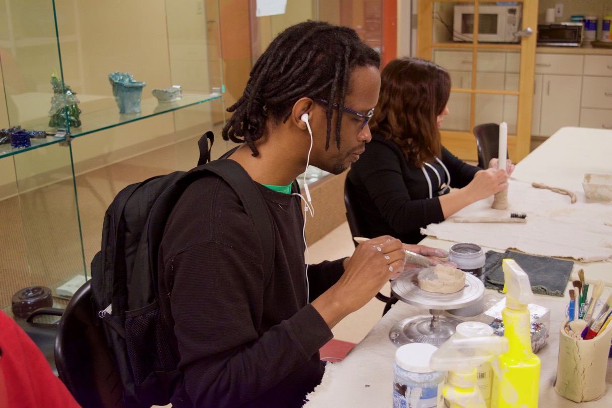 Marqus glazes the clay on a lazy susan for a votive candle holder he is making