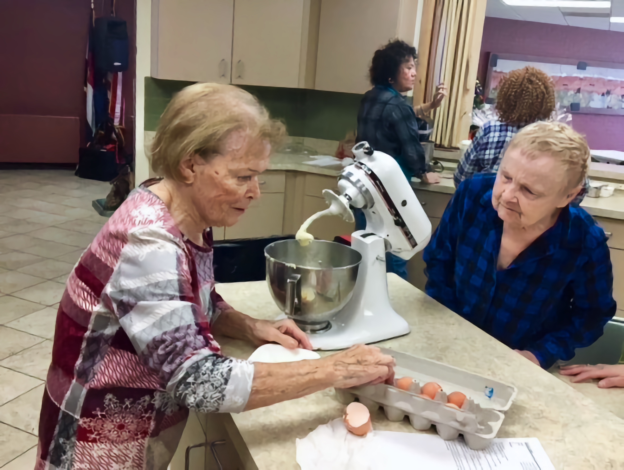Mary Ann cracks eggs to use in the batter for home made cookies. Diane looks on with encouragement