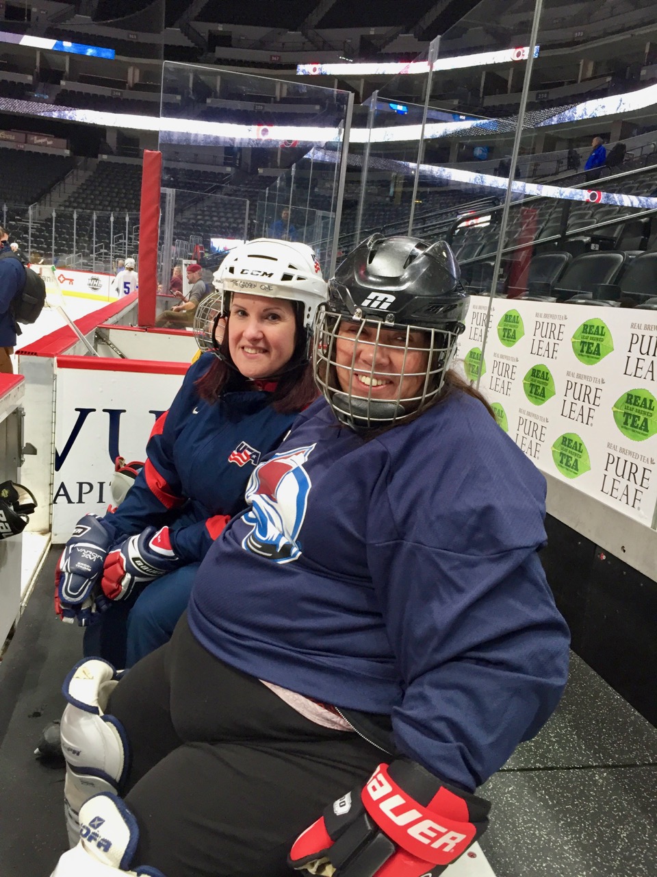 A group of CCB students sit on a bench and put on hockey gear.