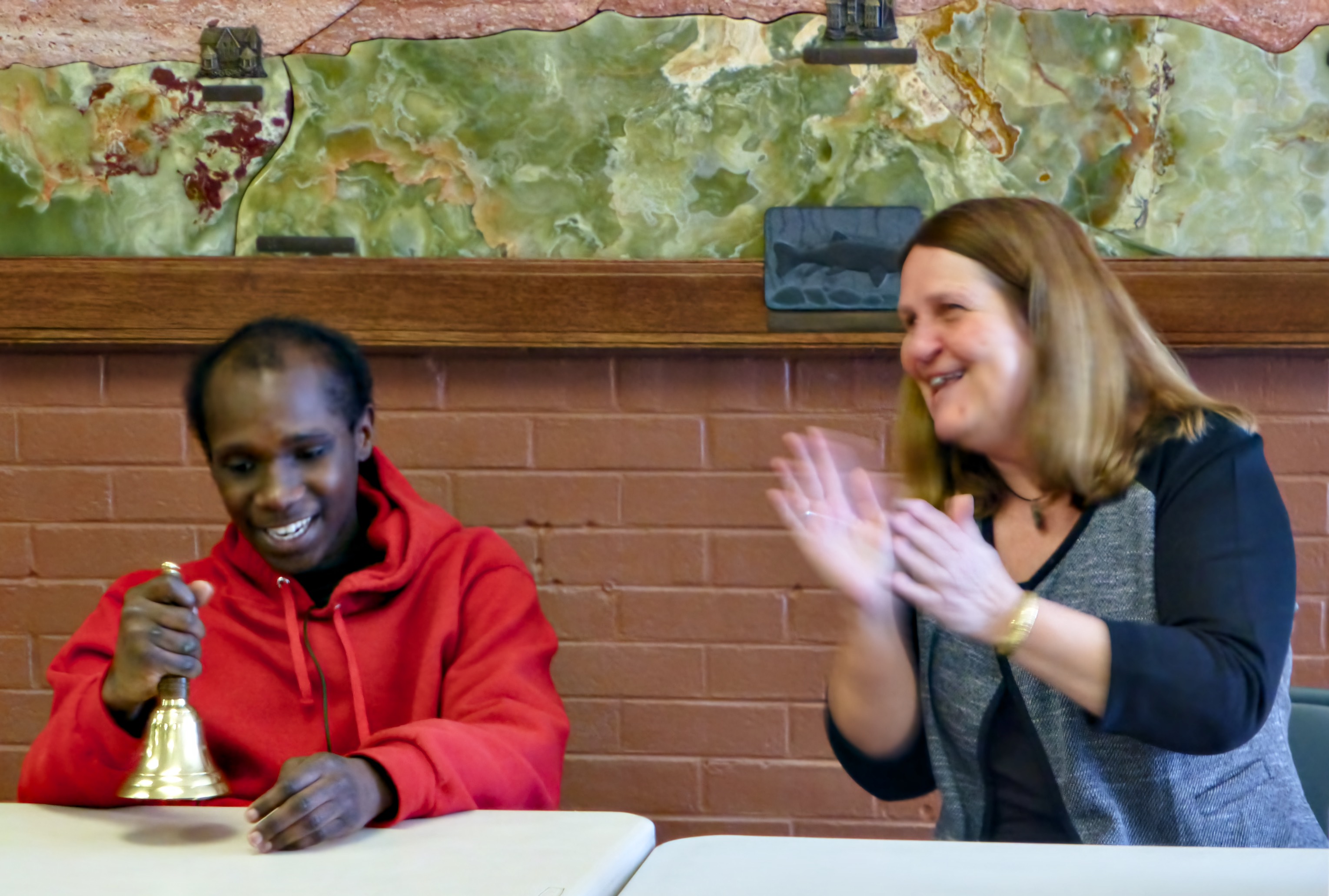 a seated young man smiles as he holds his bell