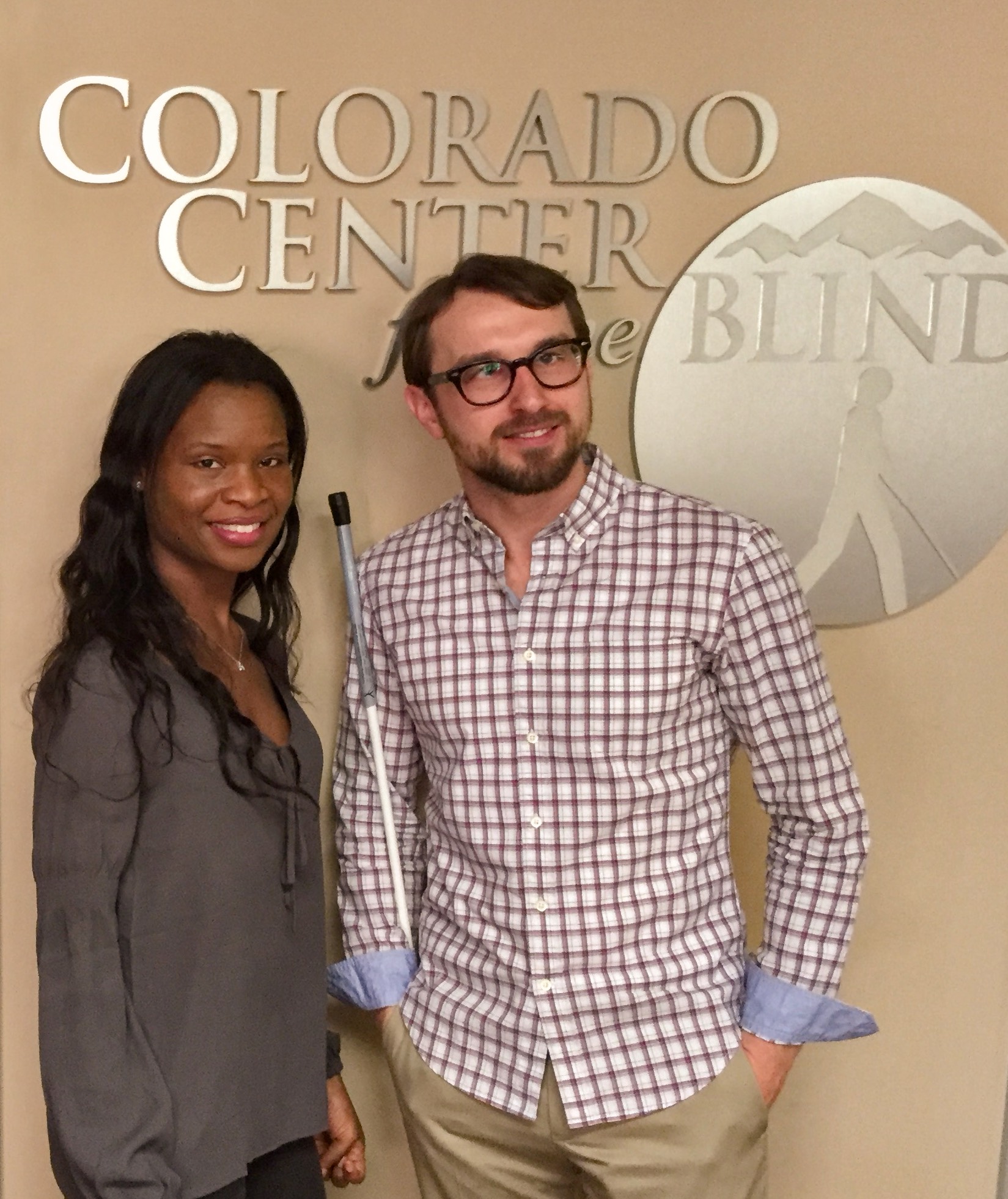 a man and woman stand before the tactile image of the CCB logo in our lobby