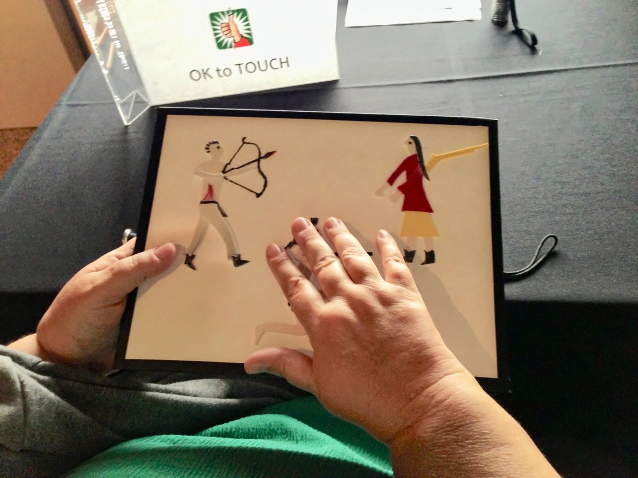 Tactile art at the Denver Art Museum—Hands explore a tactile image at the Denver Art Museum. A sign reads: OK to Touch