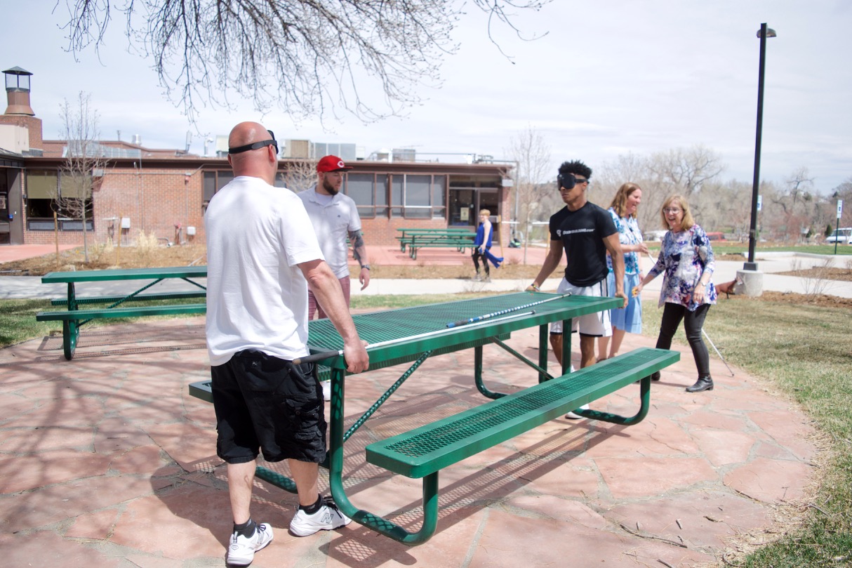 Omar, Charles and Kameron move picnic tables while Julie and Duncan figure out placement