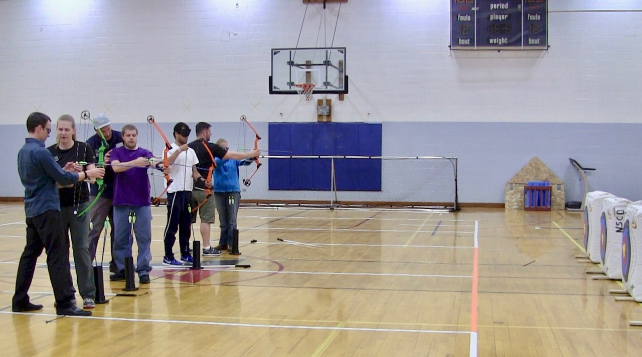 Petr, Mike, Chaz and C.G. gripping their bows to take aim with guidance from NSCD Instructors