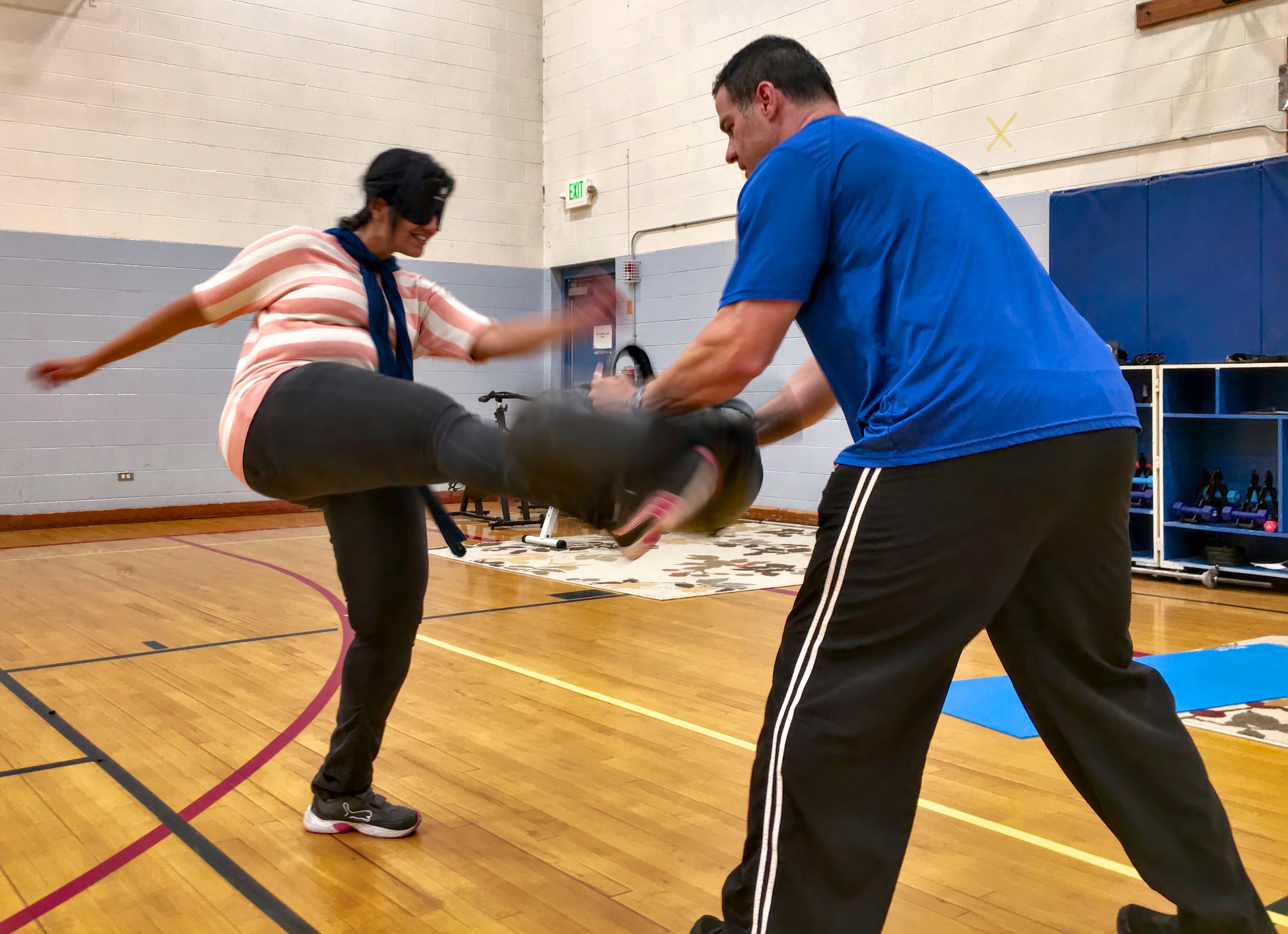 Woman takes her kick at the pad held by her instructor