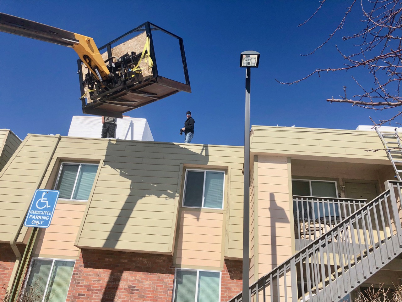 Roofing crew on top of McGeorge Mountain Terrace Apartments with snow blowers