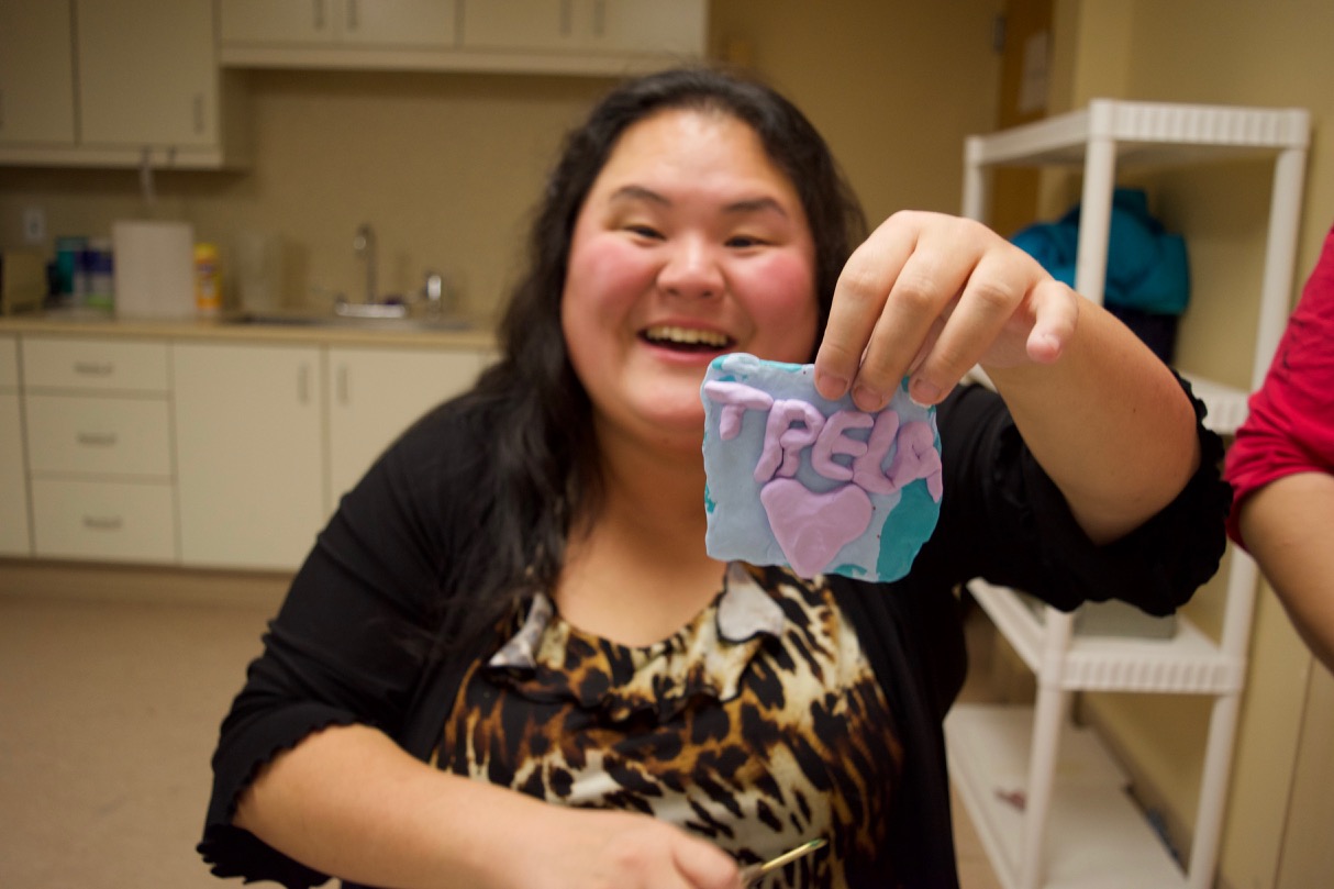 Showe holds up a clay ornament she made that spells out Trela with a heart underneath