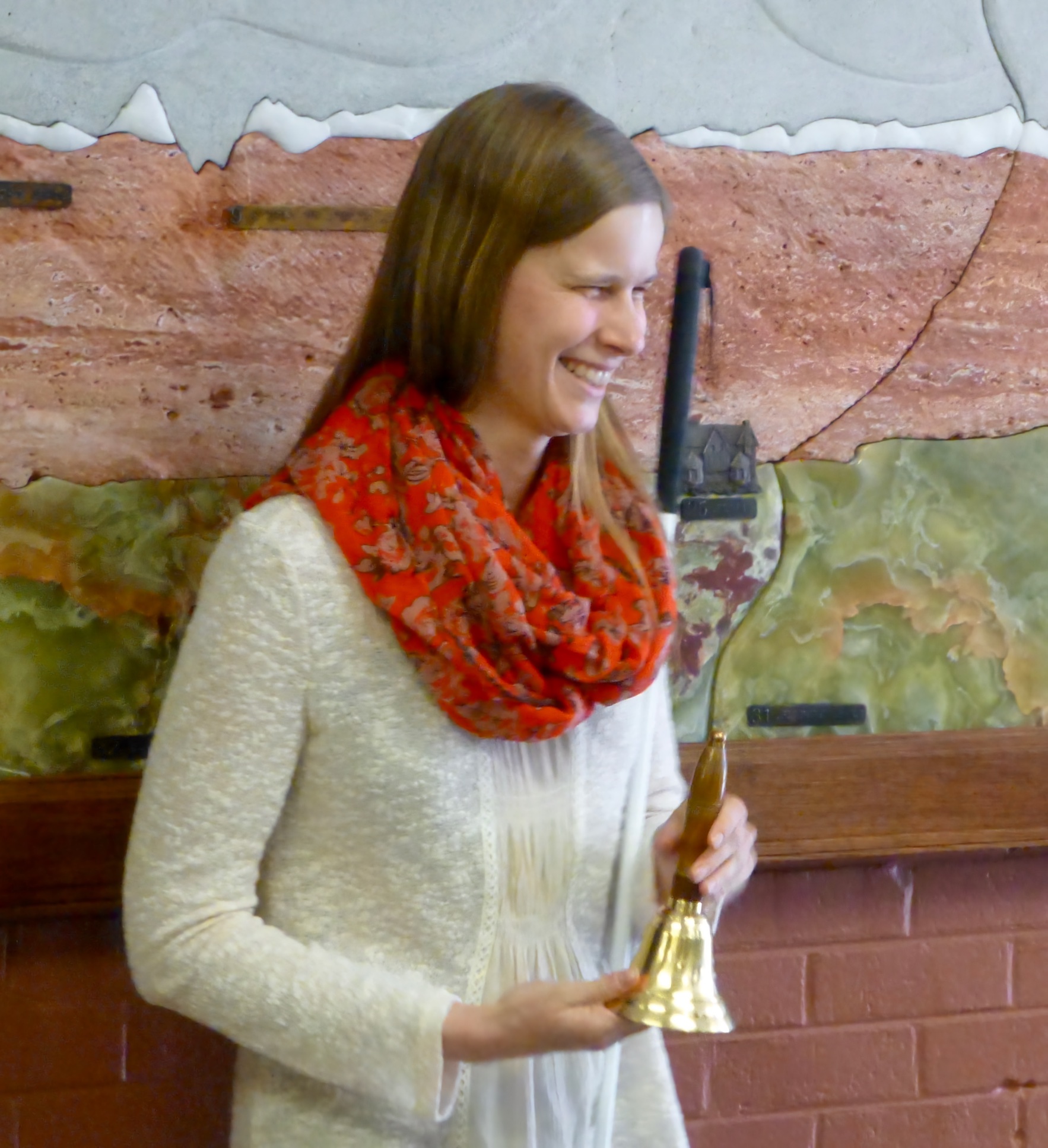 a young woman grins as she holds her bell of freedom