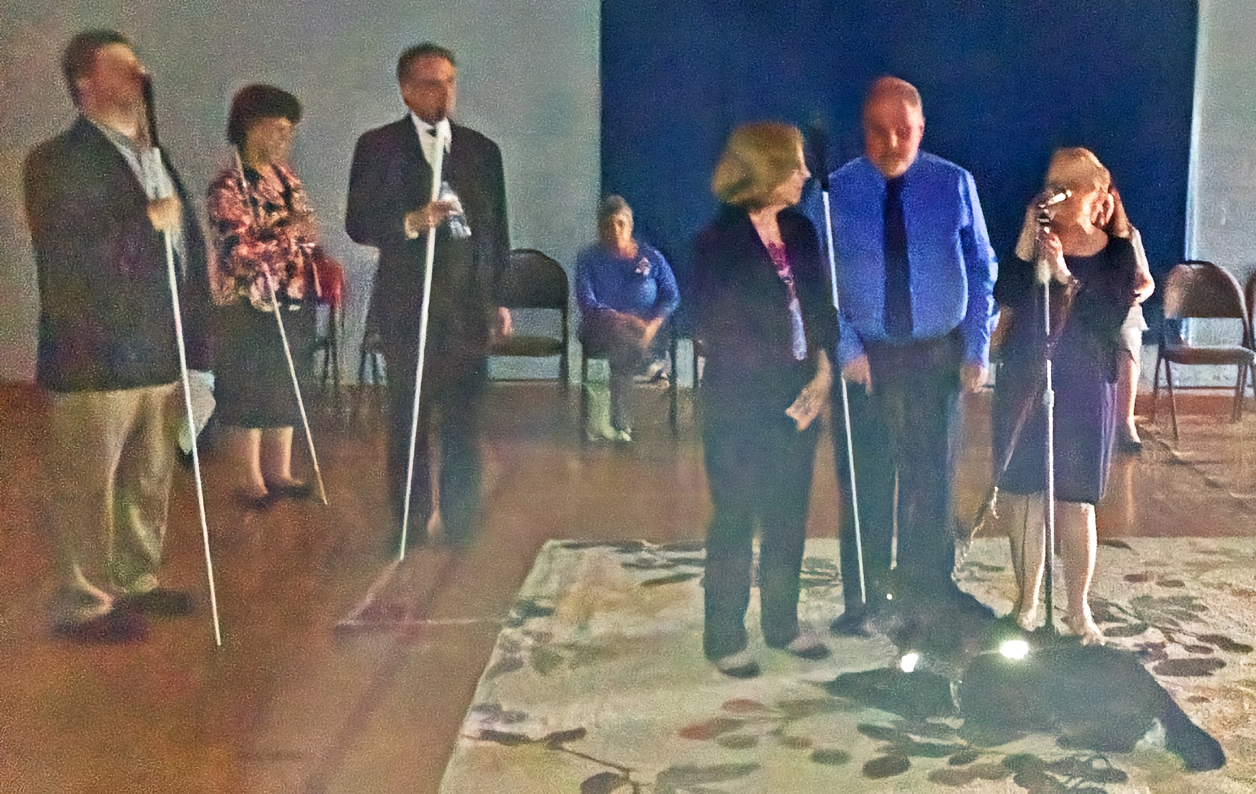 Three people stand at the front of a dimly-lit gym