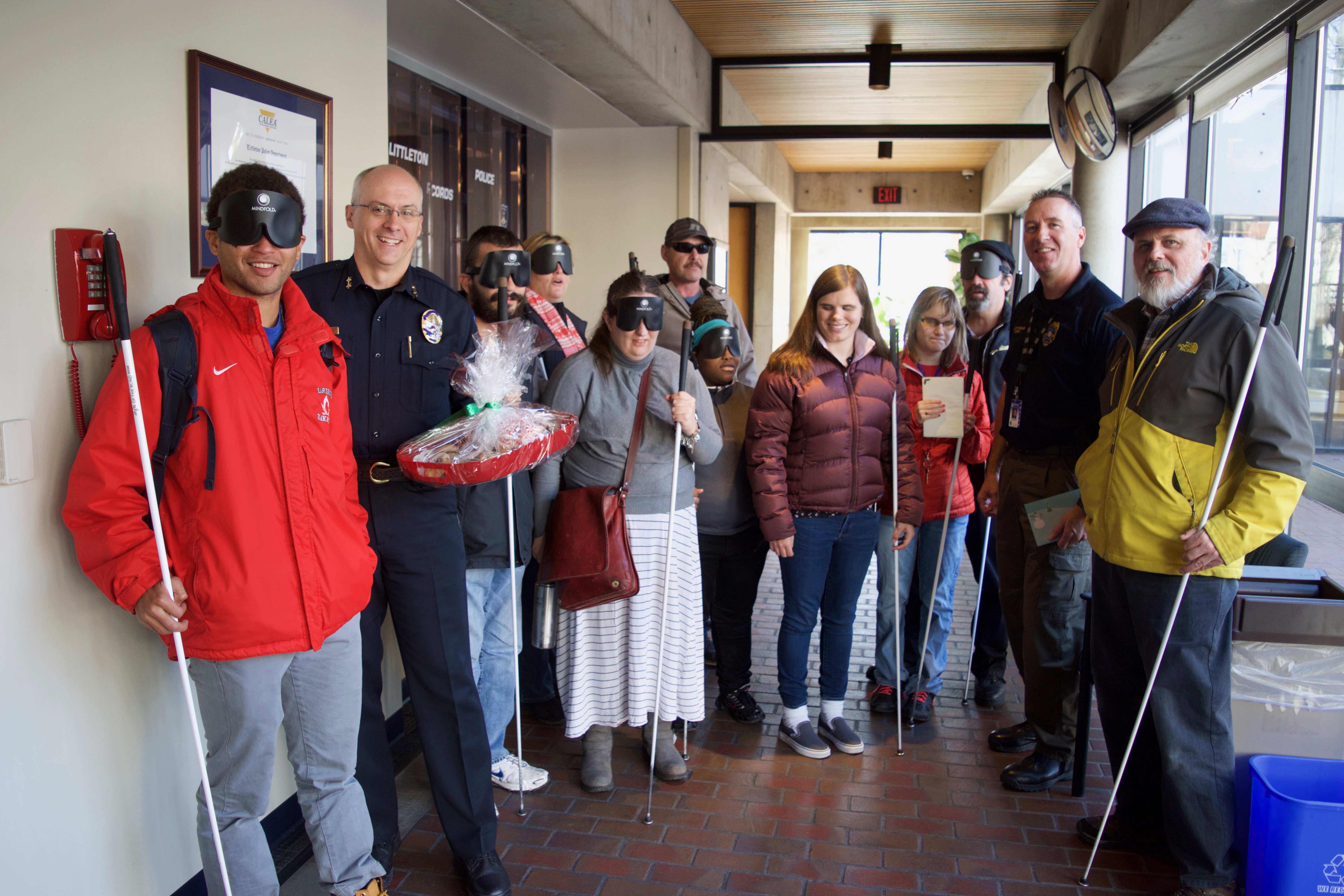 Two police officers pose with a group of CCB students who brought them a large tray of goodies and a Christmas Card