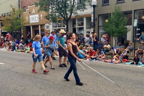 Blind Senior in a red hat marches in the Parade with a group from the Colorado Center for the Blind