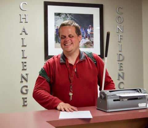 a smiling man types on the Brailler