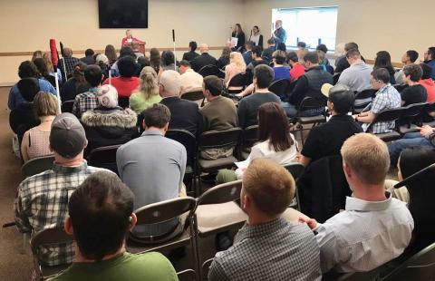 Diane McGeorge welcomes a packed room of attendees from the podium