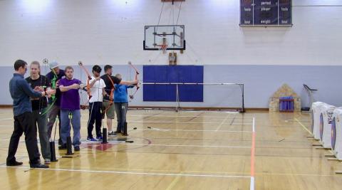 Petr, Mike, Chaz and C.G. gripping their bows to take aim with guidance from NSCD Instructors