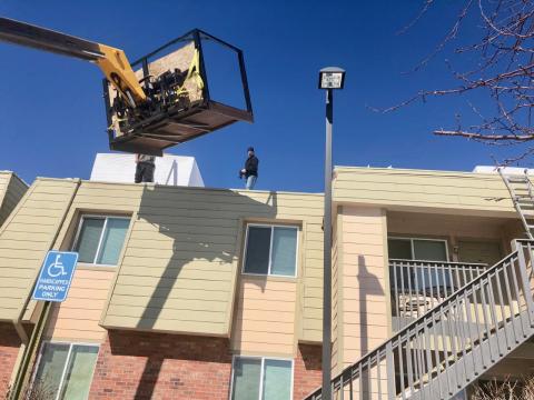 Roofing crew on top of McGeorge Mountain Terrace Apartments with snow blowers