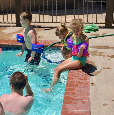 Two little girls dangle feet into the pool, making the most of summer—fun and learning!