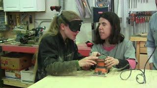 Julie and Serena sand an oak table top