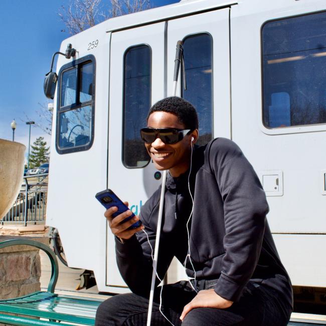 Loren listens to the news on his phone while waiting on a train