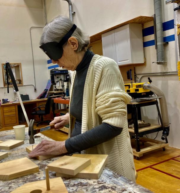 One of the In Charge students hammers a nail into the edge of a board to make a bird house