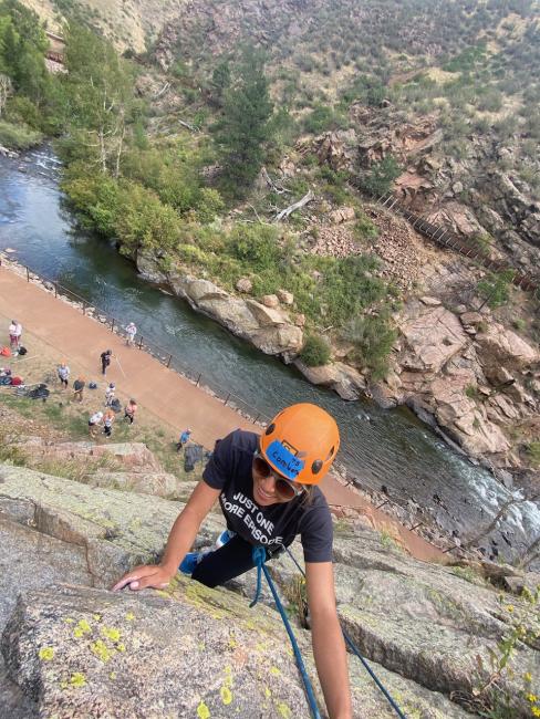 A young Blind woman smiles at the top of the rock, overlooking fellow students scattered below in Clear Creek Canyon.