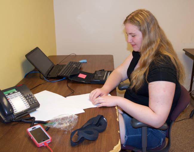 Anna reads through a Braille list of Newsline users for a survey