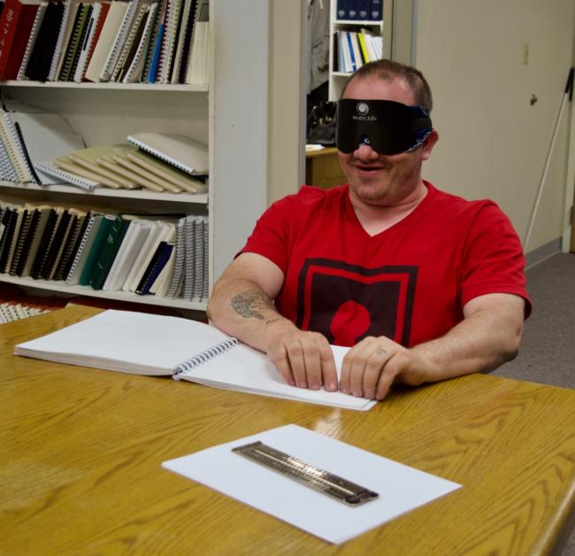 Charles S. reading from his Braille instruction book