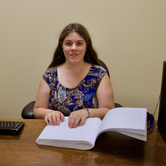Chris P. reading Braille at her desk