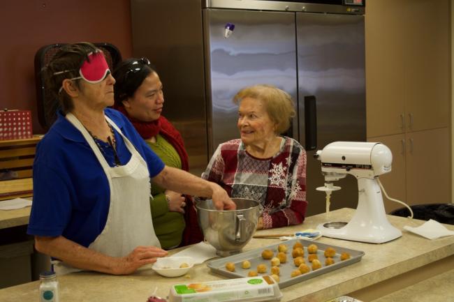 Dee and Mary Ann form cookies out of dough from a mixing bowl