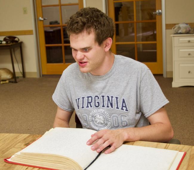 Matt at CCB reading a Braille book