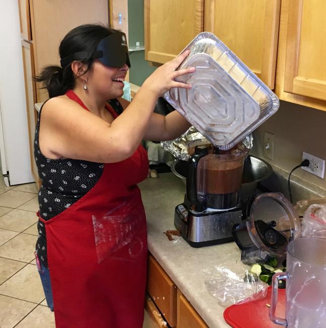 Young woman in sleepshades pours a sauce into a hotel pan