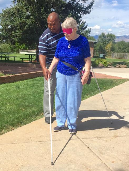 Wayne shows student how to hold the cane correctly in an outdoor travel lesson on the sidewalk in front of the center