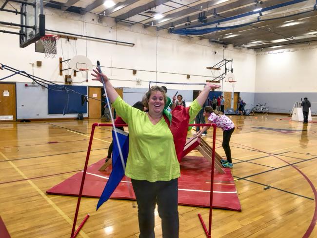 Jenny C. raises her arms in victory as she goes through the finish line of the obstacle course