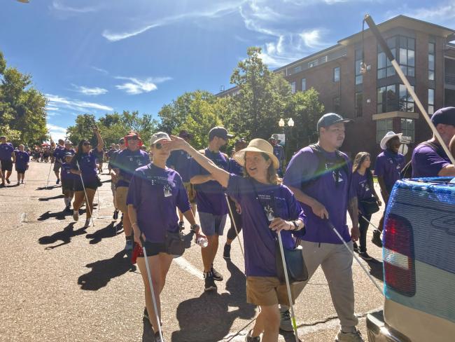 Front - Heather waves and Jonathan walks beside her in the 2024 Littleton Western Welcome Week Parade
