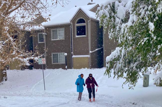 Front - Travel Instructor Ernesto-and-his student Megan-smile as they return in the falling snow from a lesson - scaled
