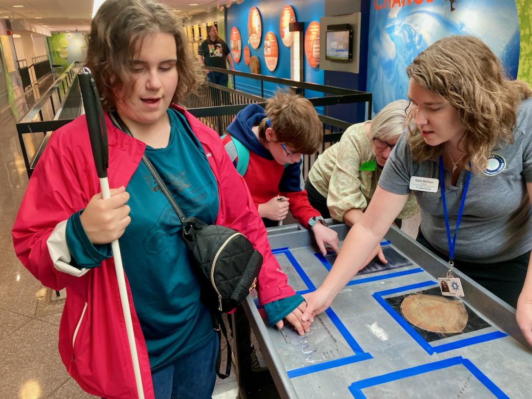 Two students have their hands on tactile graphs at NCAR