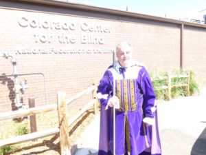Tom Anderson in a latter-day purple velvet suit beside CCB's sign