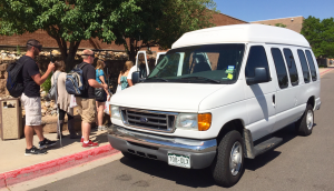 A group of students with shopping bags are lined up to get into the Center's 12 passenger van