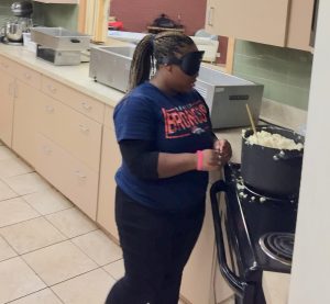 Brittany T. at the electric stove with a pot of mashed potatoes