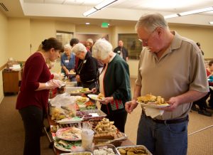 Looking down the line at the food table at the Senior Christmas Party - Anahit is serving and Gary is holding a a nice plate full of goodies