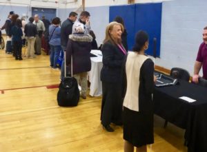 A large gathering along the tables at the exhibit hall at the Career and College Seminar