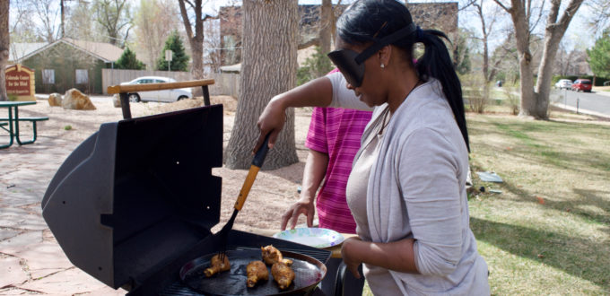 Laura in sleepshades tends chicken on the grill