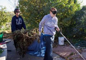 Tyler leads the way as he and Master Gardener Volunteer Barb P. carry a tarp loaded with stems and leaves pulled up from the garden