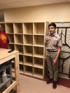 Alex LaBarre stands next to the new cubby shelves that he helped assemble for the art room