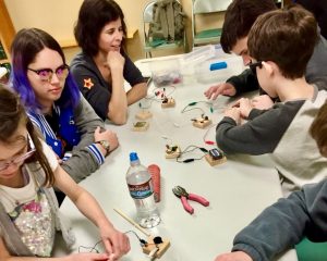 A view down the table of blind youth getting hands on experience making simple circuits
