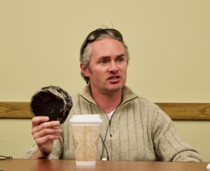 Craig Fitzpatrick holds up an adapted hockey puck while he gives a talk about Blind Hockey at the Colorado Center for the Bind