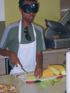 A student slices yellow squash on a cutting board.