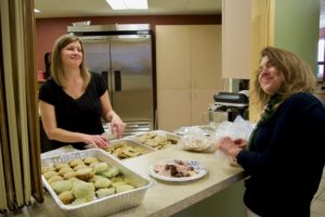 Stephanie P. and Delfina arrange trays of home made cookies, candy, muffins and other treats