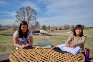 Stephannie and Eliza take advantage of the warm weather and study Braille outside