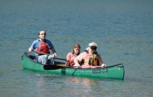 Holly, Cody and Lia paddle a green canoe at Bear Creek Lake
