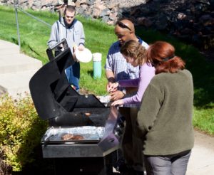 Jenny B. taking her turn at the BBQ grill with Shon's instruction making a burger while Matt and Marlene watch